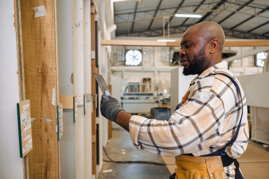 staff male black worker working in wood furniture industry factory checking selecting plywood wooden board type material in stock warehouse.
